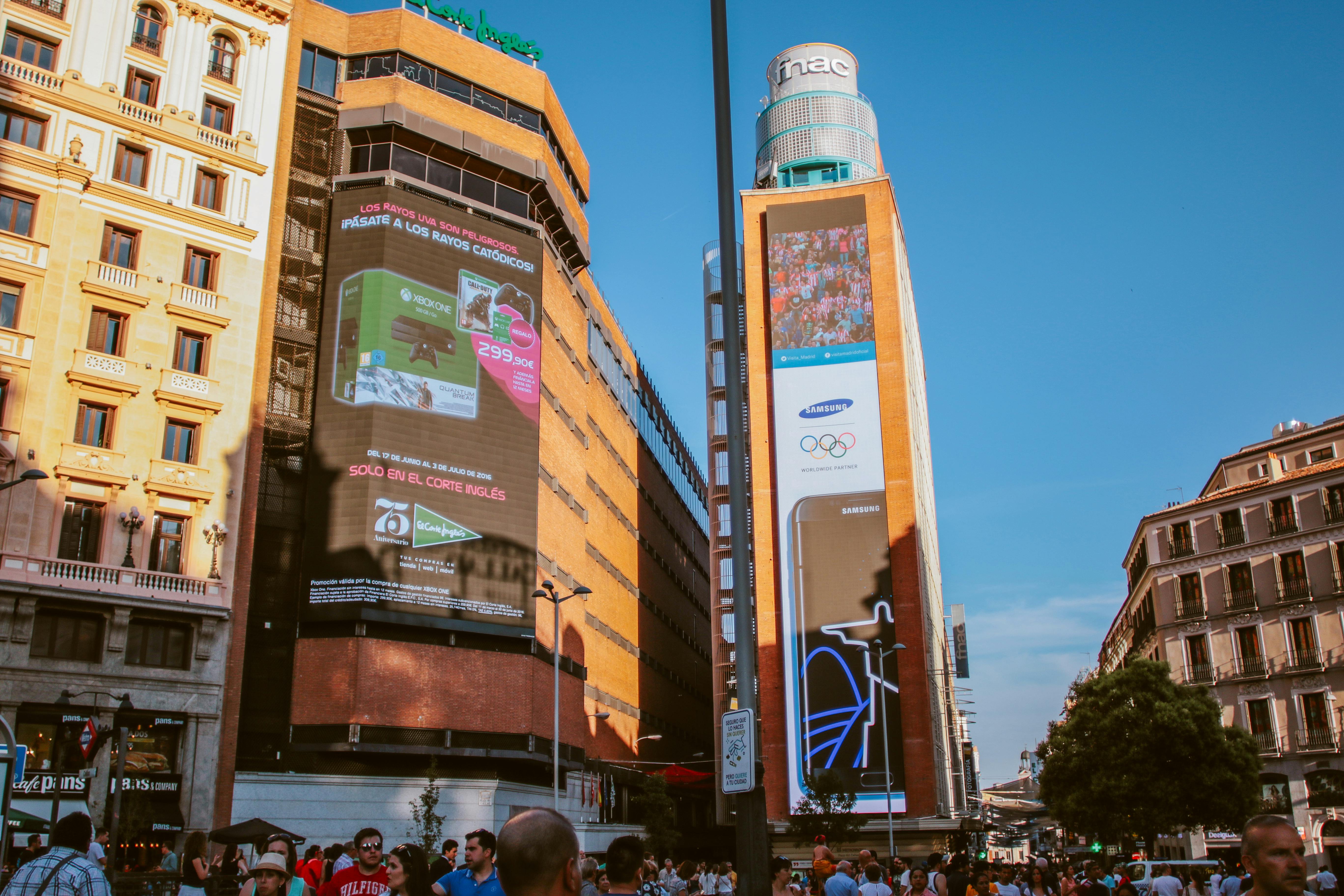 Crowded urban scene with iconic digital billboards and diverse architecture in daytime.