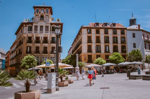 Free Vibrant street scene in Madrid showing classic architecture and bustling plaza activity. Stock Photo
