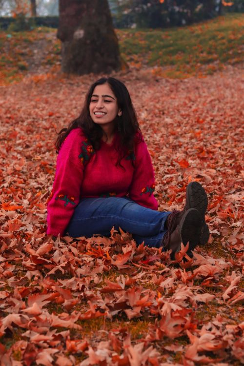 Free Woman enjoying a peaceful moment amidst colorful fallen leaves in a park during fall Stock Photo