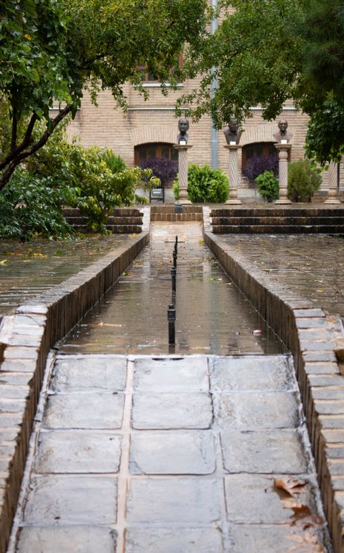 Free Tranquil pathway with reflective water and lush greenery in Tehran, Iran. Ideal for nature lovers. Stock Photo