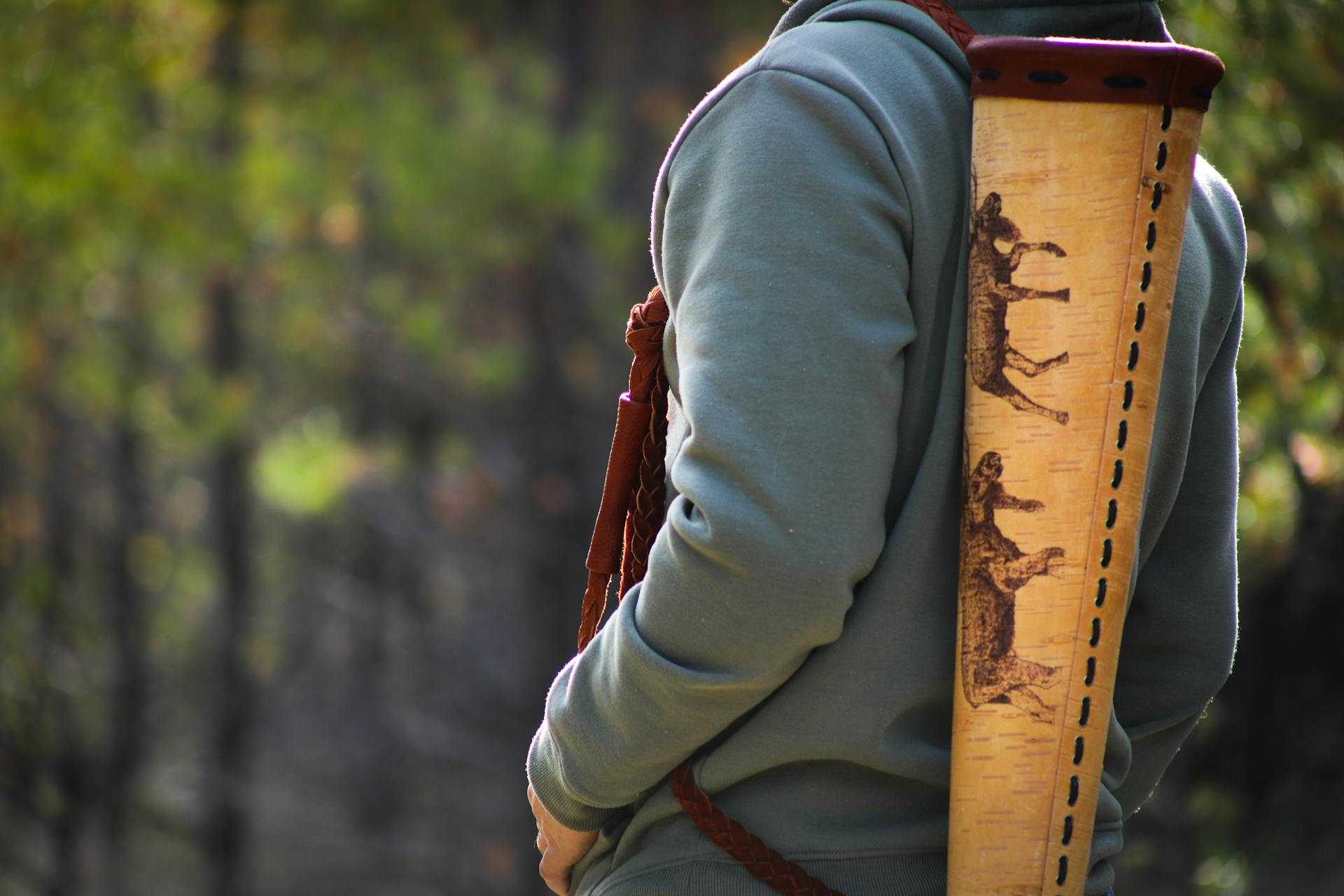 A person with a decorated quiver strapped to their back in a forest setting, showcasing outdoor adventure.