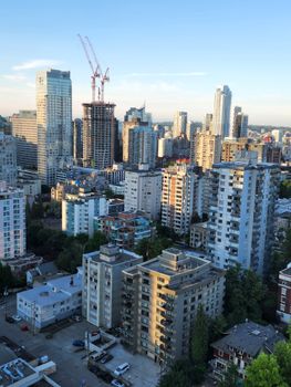 Aerial view of Vancouver's urban skyline with modern high-rise buildings and construction cranes.