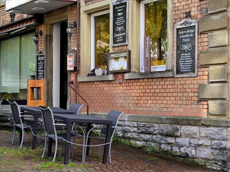 Cozy outdoor seating area of a restaurant with a brick facade featuring classic decor and menu boards.