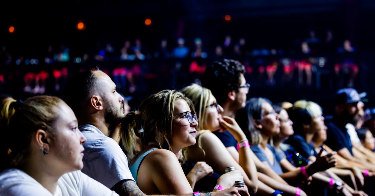 Taylor Swift performing on stage during Eras Tour, crowd with glowing wristbands