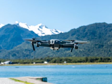 A drone flying over a serene lake with majestic mountains in the background.
