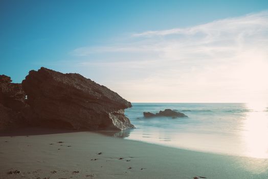 Serene beach landscape at sunrise with rocks in Conil de la Frontera, Spain.