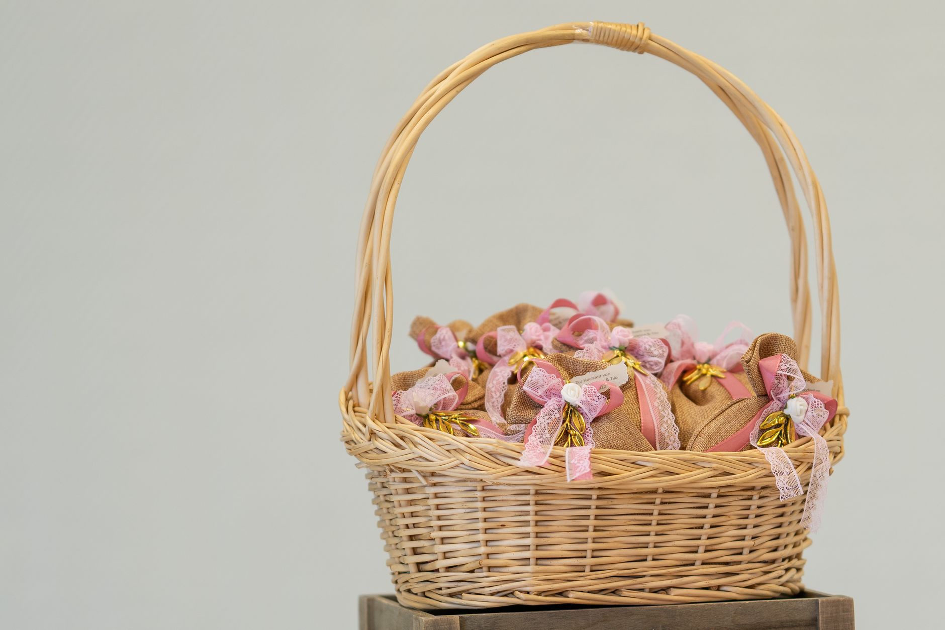 Close-up of a wicker basket filled with decorative gifts wrapped in fabric bows.