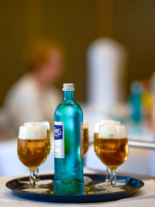 Bottled Water in the Middle of Glasses of Beer