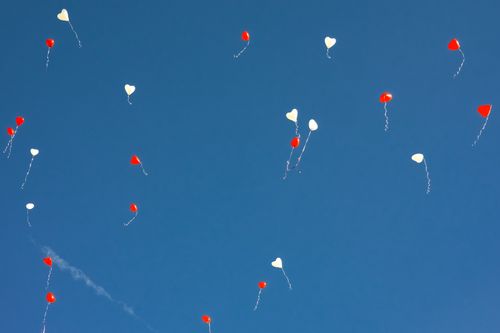 Free Red and white heart-shaped balloons floating peacefully in a clear blue sky. Stock Photo