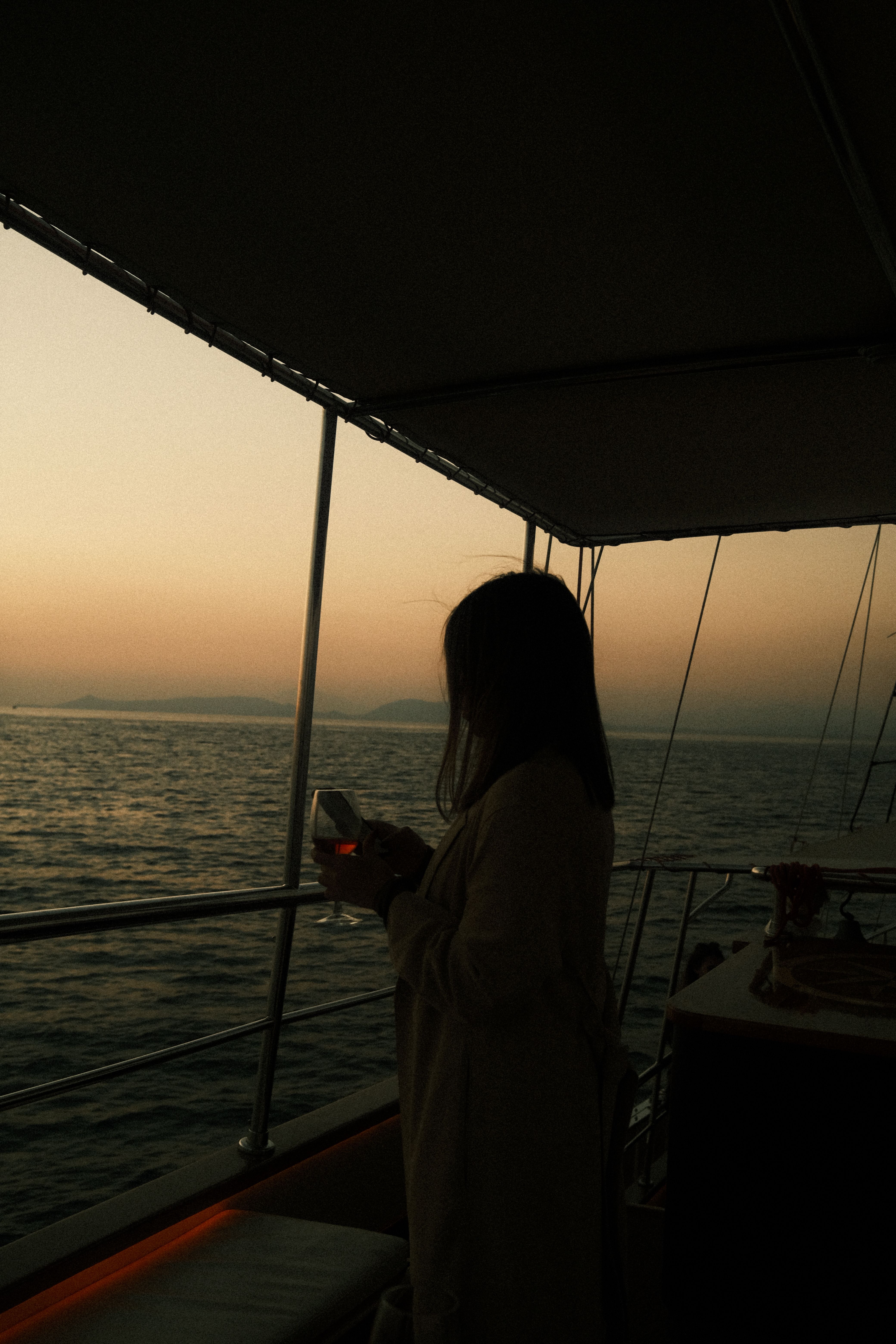 A serene moment on a yacht sailing in Athens as a woman enjoys the sunset over the Aegean Sea.