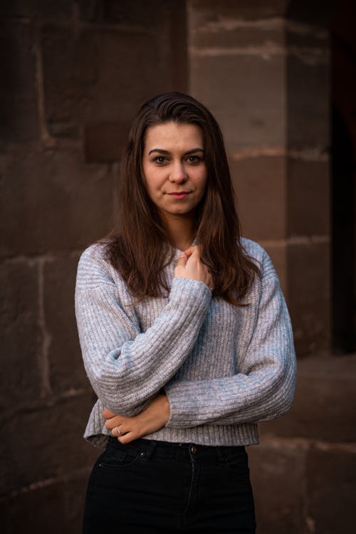 Young Woman in a Sweater Standing in front of a Building