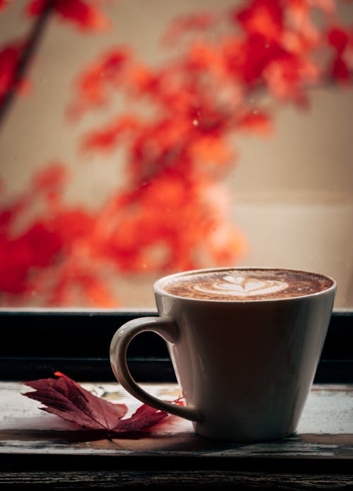 A Cup of Coffee Beside an Autumn Leaf