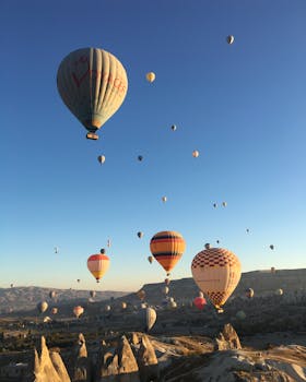 Hot air balloons soar over Cappadocia's unique rock formations at sunrise, offering a breathtaking aerial view.