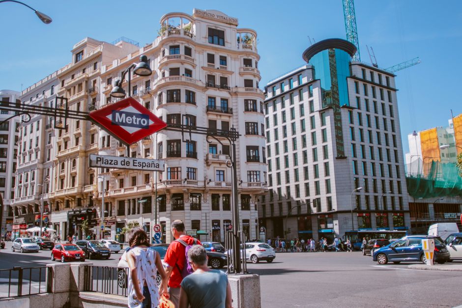 Vida urbana bulliciosa en la Plaza de España con arquitectura icónica y cartel del Metro.