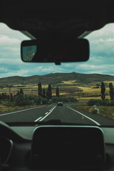 View from car of winding road and countryside landscape, ideal for travel themes.