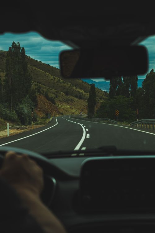 Free Experience a winding drive through picturesque hills, captured from a car's interior. Stock Photo