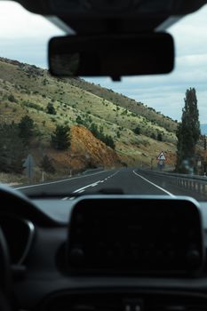 View of a winding road through a mountainous valley from inside a car.