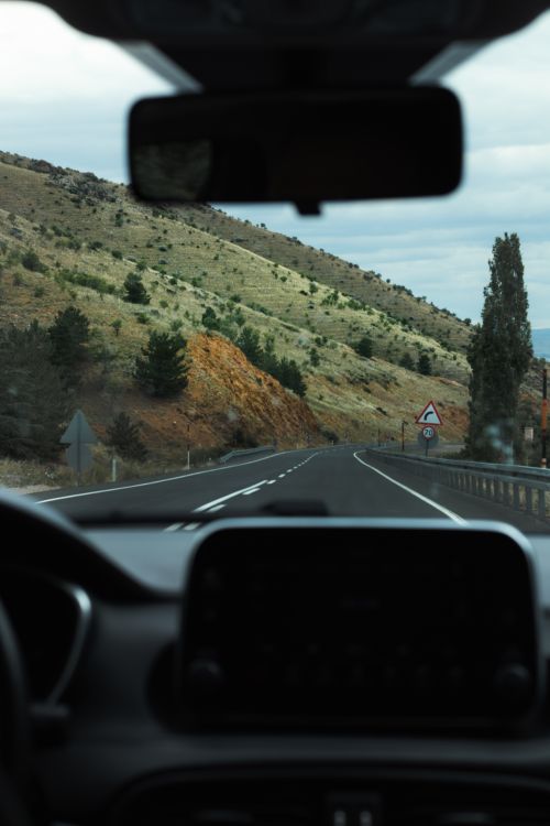 Free View of a winding road through a mountainous valley from inside a car. Stock Photo