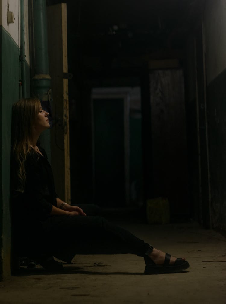 Woman Sitting In A Dark Corridor 