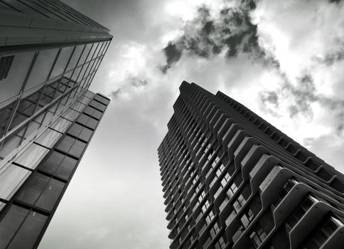 从低角度俯瞰现代摩天大楼，多云的天空映衬出建筑设计的轮廓