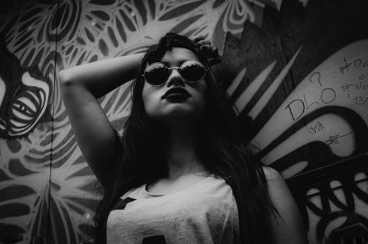 Stylish black and white portrait of a woman posing with graffiti art background.