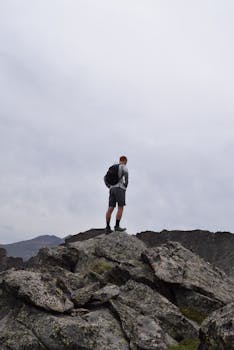 A hiker stands on a rocky peak in Estes Park, Colorado, showcasing adventure and determination.