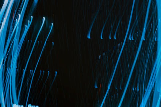 Dynamic abstract image of swirling blue light trails on a dark background.