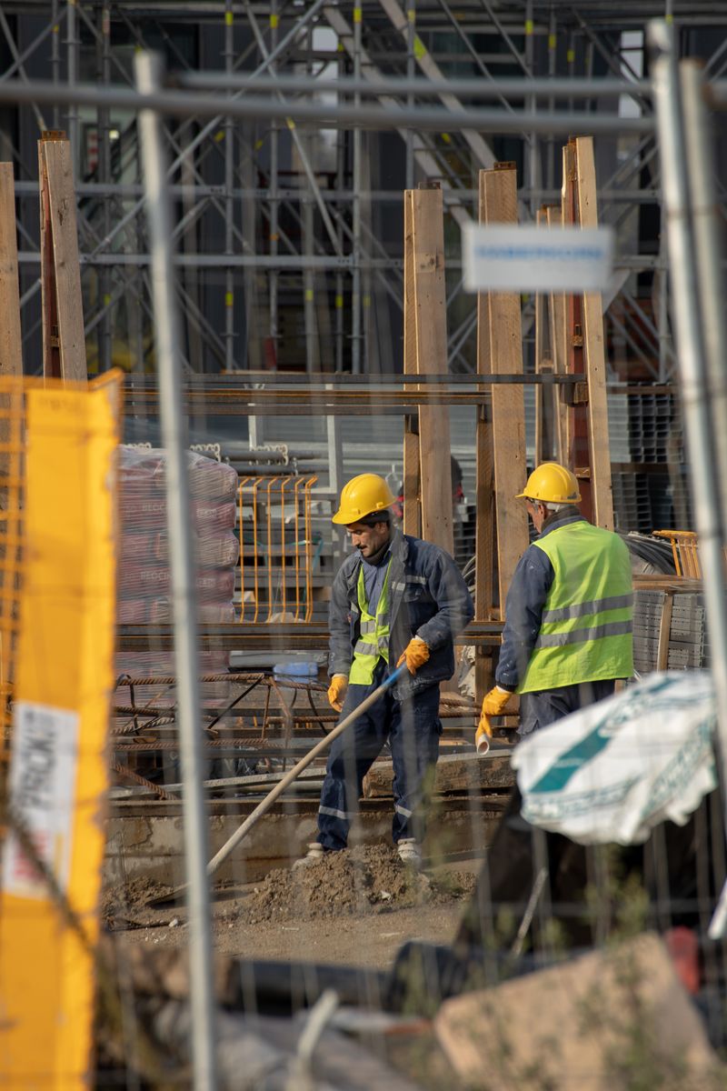 Two construction workers in safety gear collaborate efficiently in a busy construction site