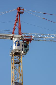 Close-up of a tower crane lifting construction materials on a sunny day.