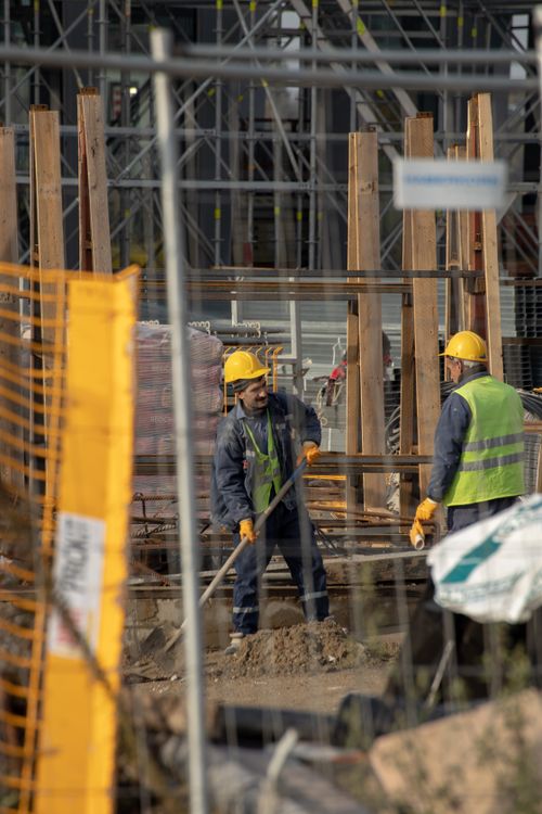 Free Construction workers in hard hats at an active building site with safety barriers. Stock Photo