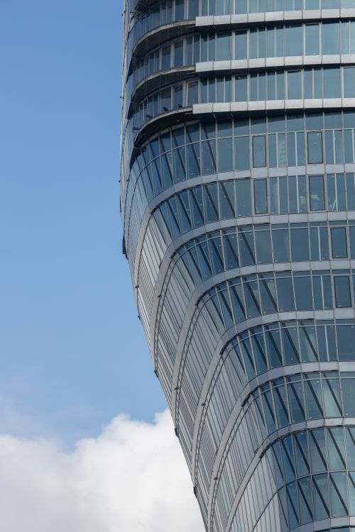 Free Close-up view of a modern glass skyscraper with a blue sky backdrop. Stock Photo