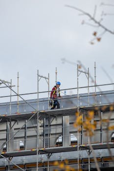 A construction worker walking on scaffolding at an outdoor building site.