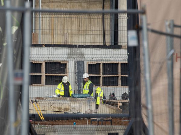 Site engineers in helmets inspecting a building under construction