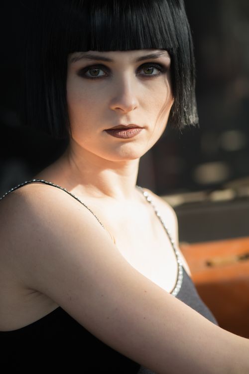 Free Portrait of a woman with short dark hair, elegantly styled makeup, and dramatic lighting. Stock Photo