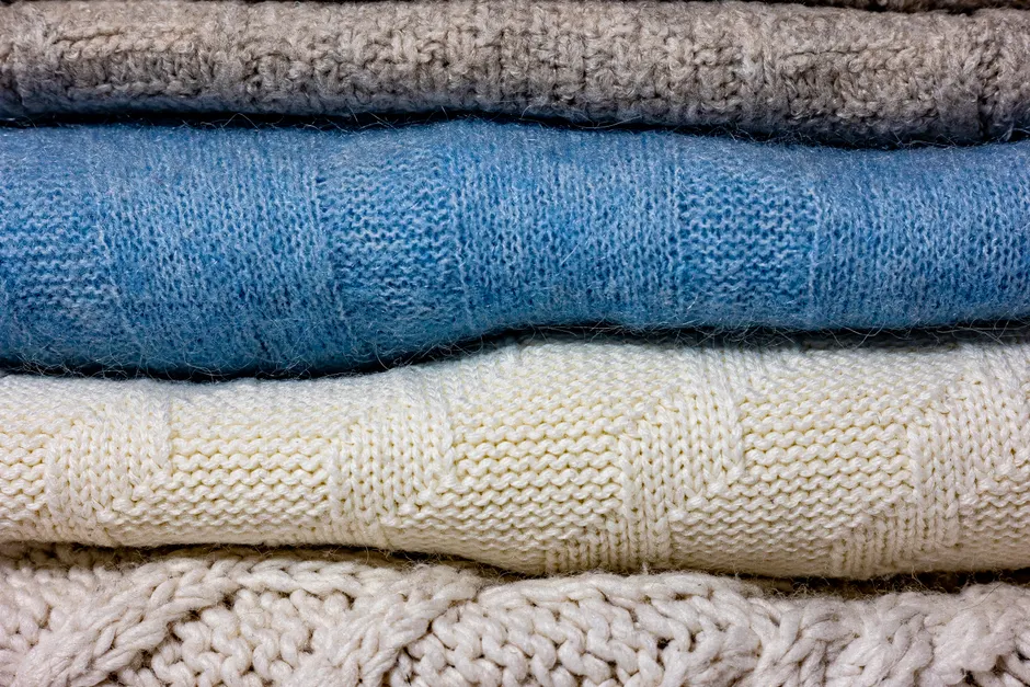 Pulls en maille tricotée empilés, gros plan sur les points et les textures