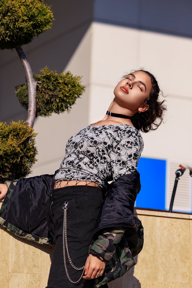 A Woman Posing Near The Plant And Concrete Wall Wearing Printed Shirt And Jacket