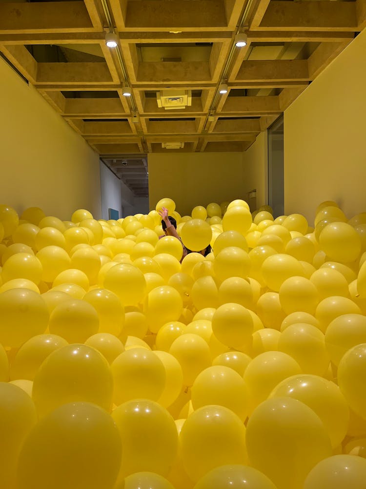 People Inside A Room Filled With Yellow Balloons