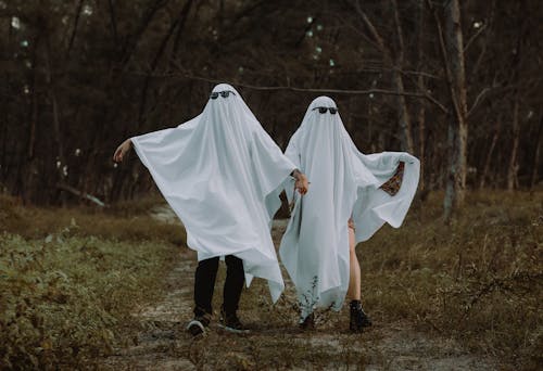 Couple Dressed as Ghosts Walking in the Forest