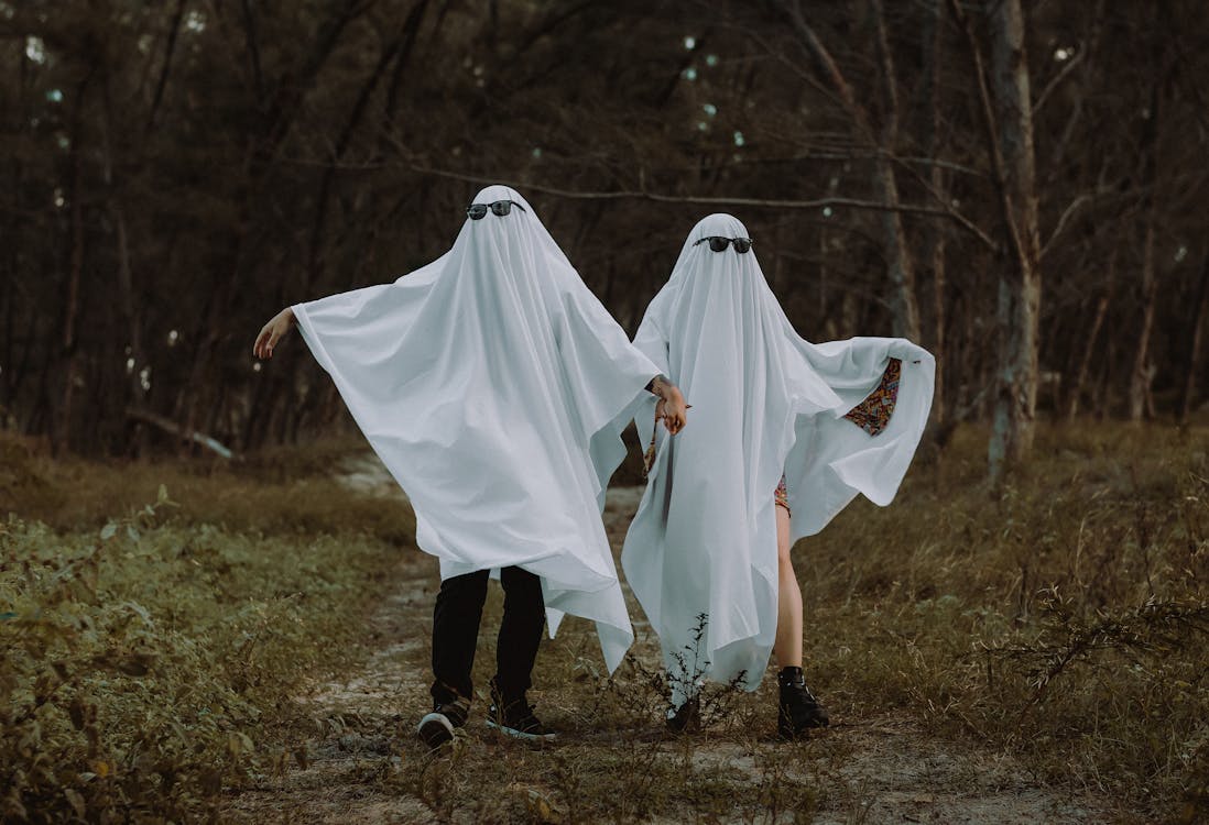 Couple Dressed as Ghosts Walking in the Forest