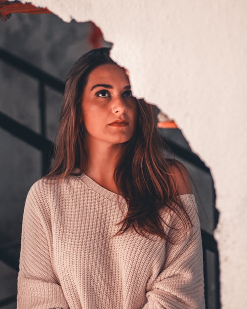 Close-up Photo of Woman Near Broken White Wall