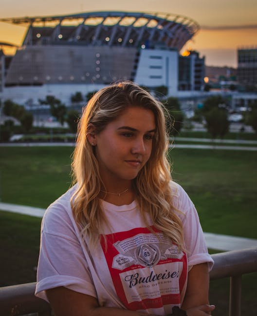 Blond woman in a park at sunset with Cincinnati stadium in the background.