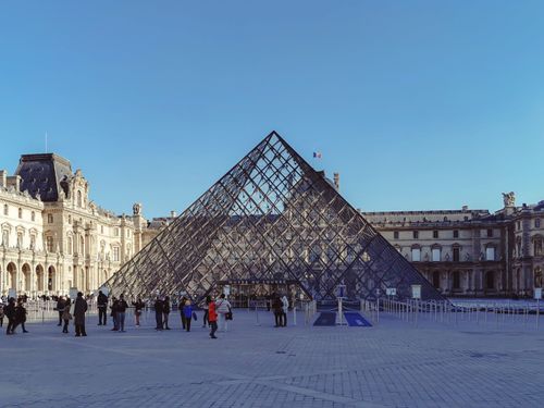 Free View of the iconic Louvre Pyramid and museum facade on a clear day in Paris, France. Stock Photo