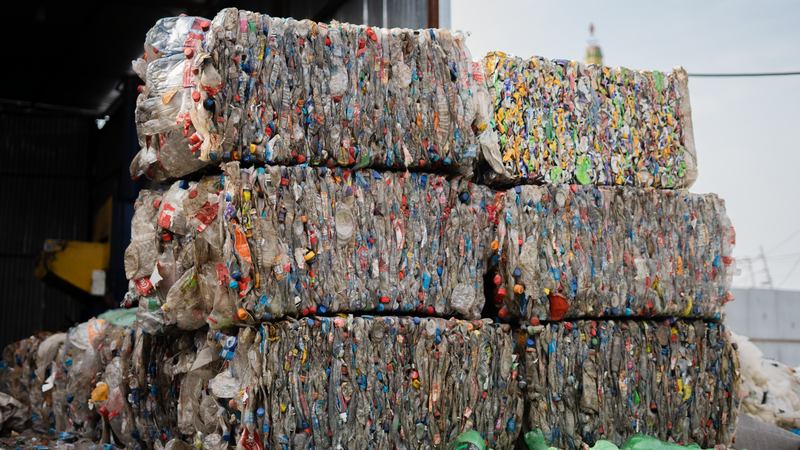 Stacked compressed plastic bottles at a recycling facility, ready for processing.
