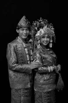 Elegant black and white portrait of a couple in traditional attire, smiling together. - Fotografer Sidoarjo