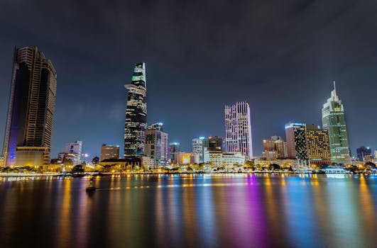 A breathtaking night view of Ho Chi Minh City's skyline with illuminated skyscrapers and reflections on the river.