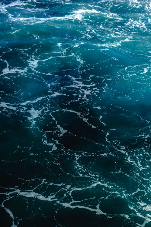 Free Captivating aerial view of turquoise ocean waves creating intricate patterns and textures on water surface. Stock Photo