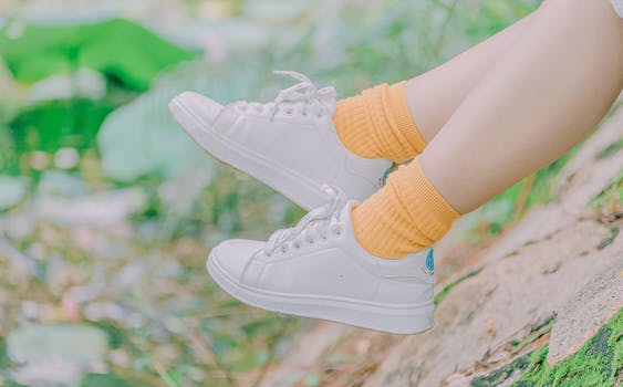 Close-up of legs in white sneakers and yellow socks outdoors, capturing youthful casual fashion.