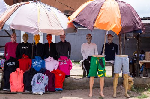Free Street market stall with various clothing on mannequins under colorful umbrellas. Stock Photo