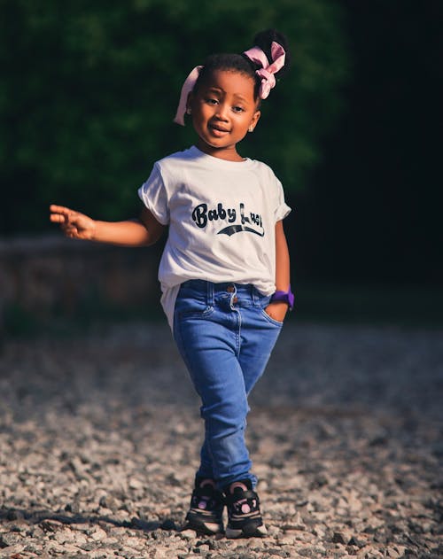 Little Girl in a T-shirt and Jeans Standing Outside 