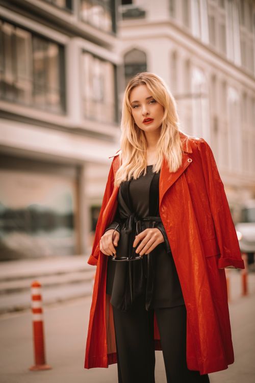 Free Stylish woman in a red coat posing confidently on an urban street, exuding elegance. Stock Photo